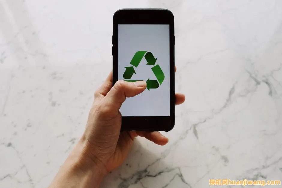 Hand holding smartphone displaying recycling symbol, promoting eco-friendly technology.