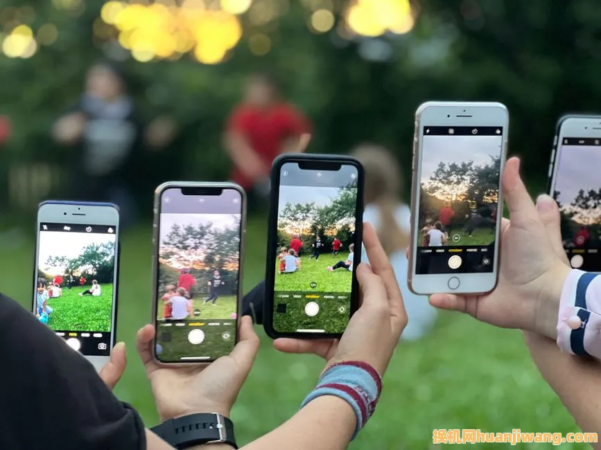 A group of people using smartphones to photograph an outdoor scene.