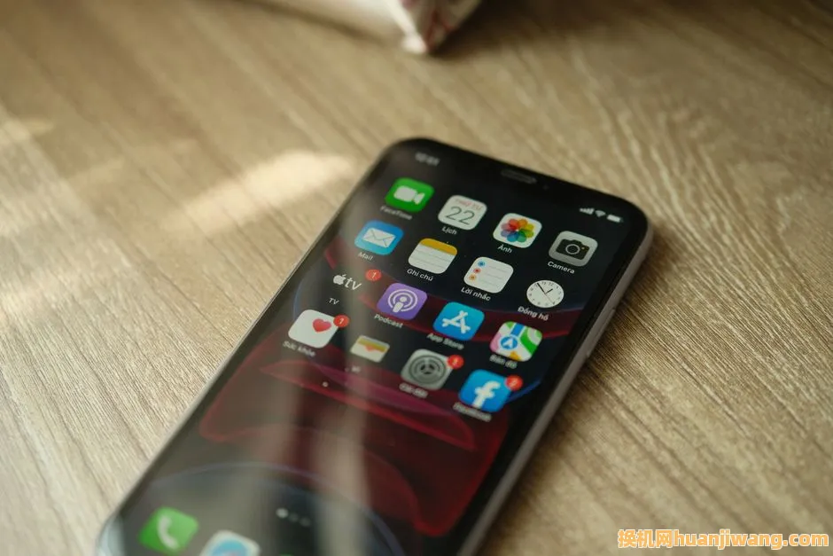 A close-up view of a smartphone displaying various apps on a wooden surface.