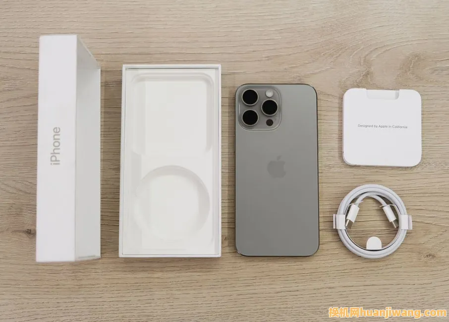 Flat lay view of the newest Apple iPhone model, box, and charging accessories on a wooden table.