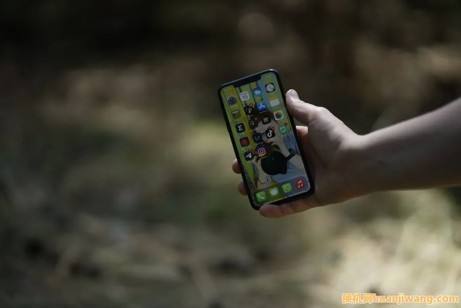 A close-up image of a hand holding a smartphone outdoors, showcasing a nature background.