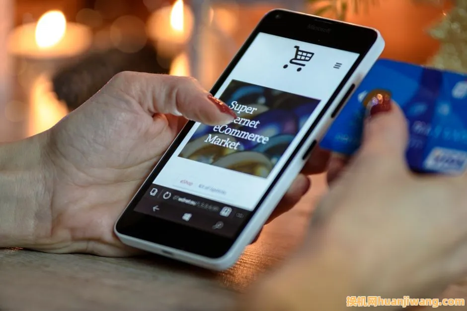 Woman using smartphone for online shopping with credit card in hand, festive background lighting.