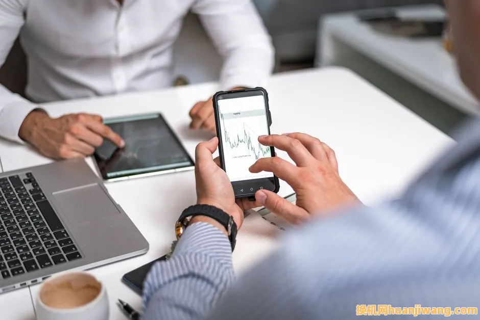 Two business professionals analyzing market trends on digital devices in an office setting.
