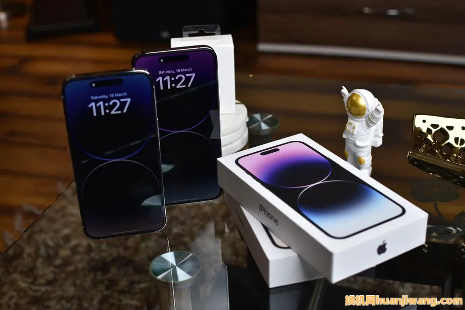 Close-up of Apple iPhone 14 Pro Max with astronaut figurine on a reflective surface.